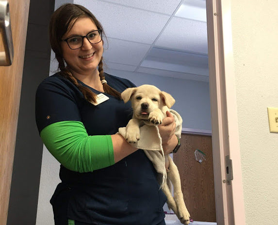 HSPPR staff smiling while holding a small tan puppy