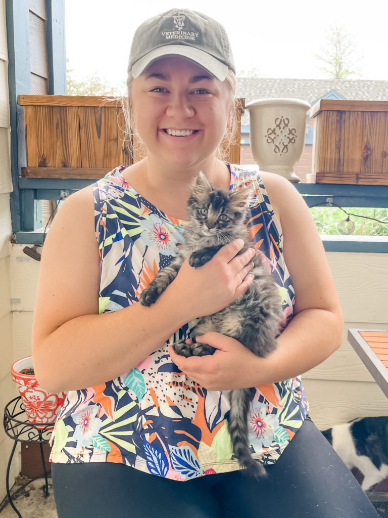Blonde woman smiling and holding her healthy, gray kitten