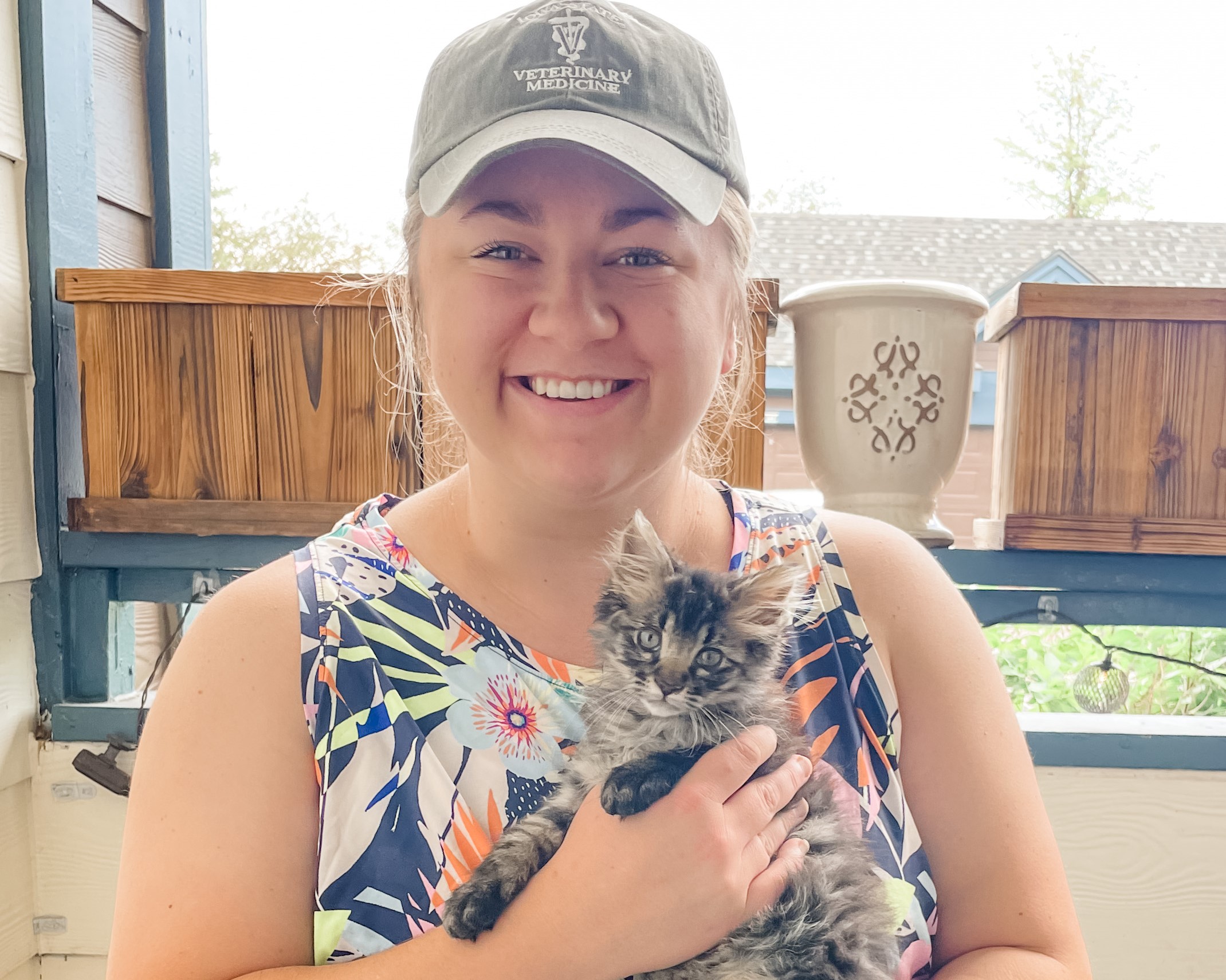 Blonde woman smiling and holding her healthy, gray kitten